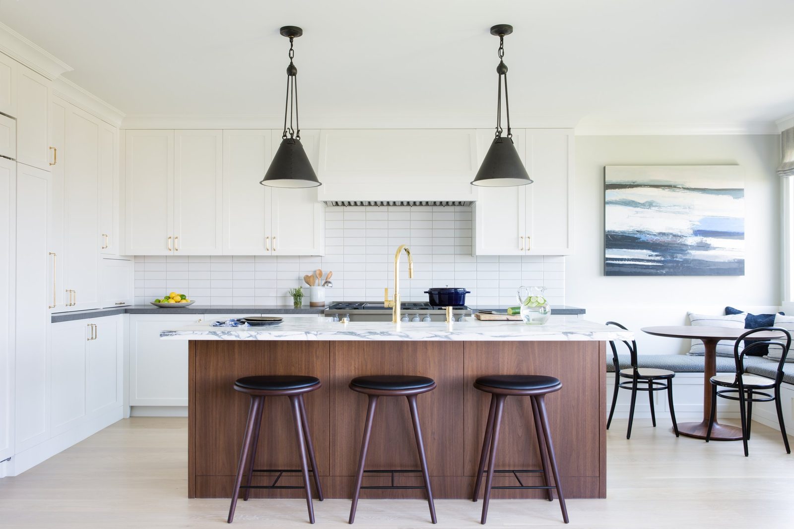 Kitchen in a Cow Hollow residence by ABD STUDIO with white cabinets, a marble-topped walnut island and black pendants
