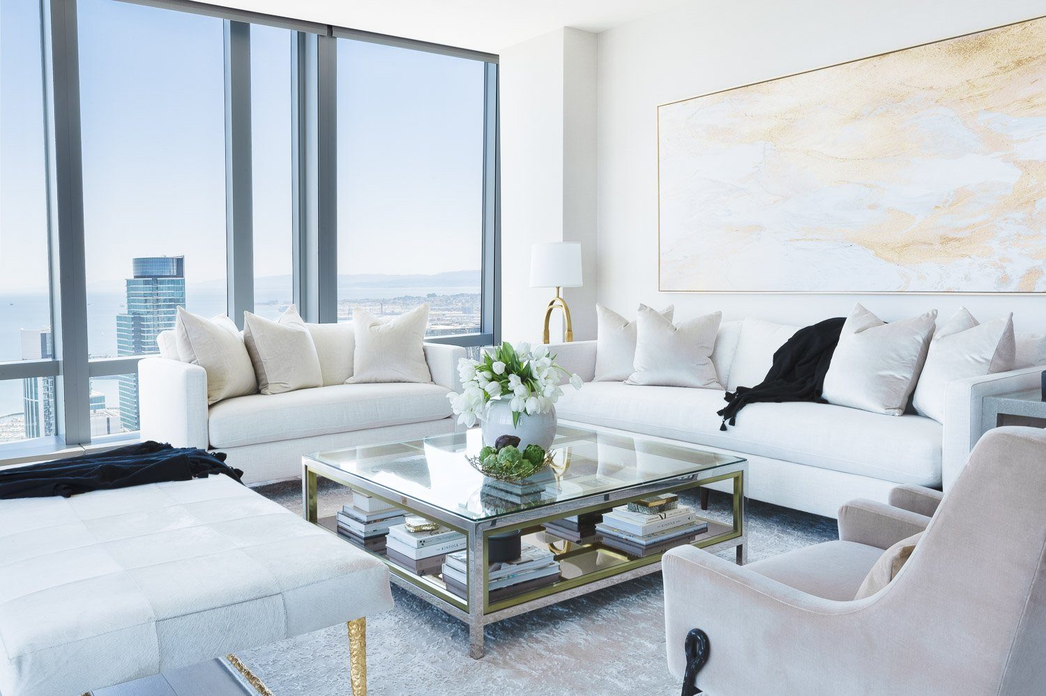 Living room in a San Francisco penthouse designed by Saga Interiors, with a white sectional and floor-to-ceiling skyline windows
